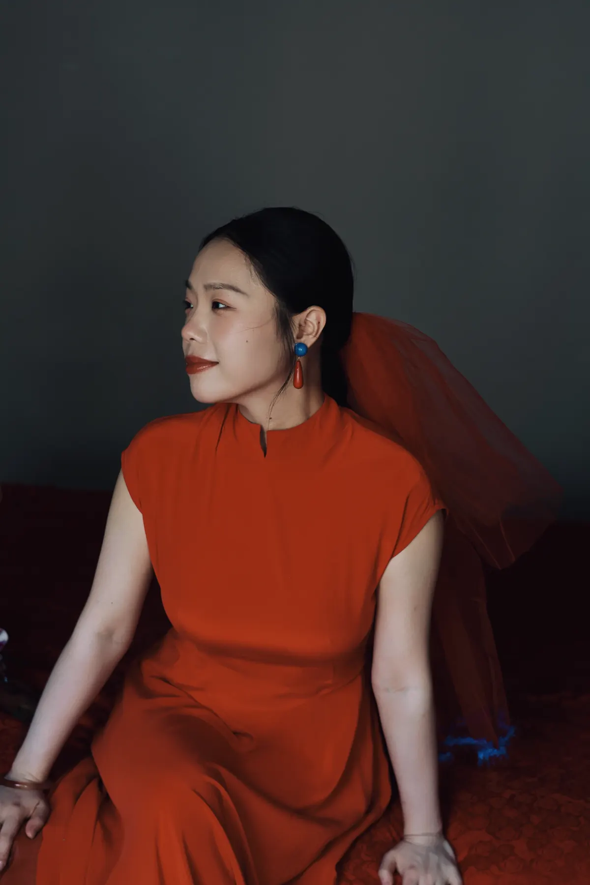 穿红色中式礼服的女性侧身坐姿肖像